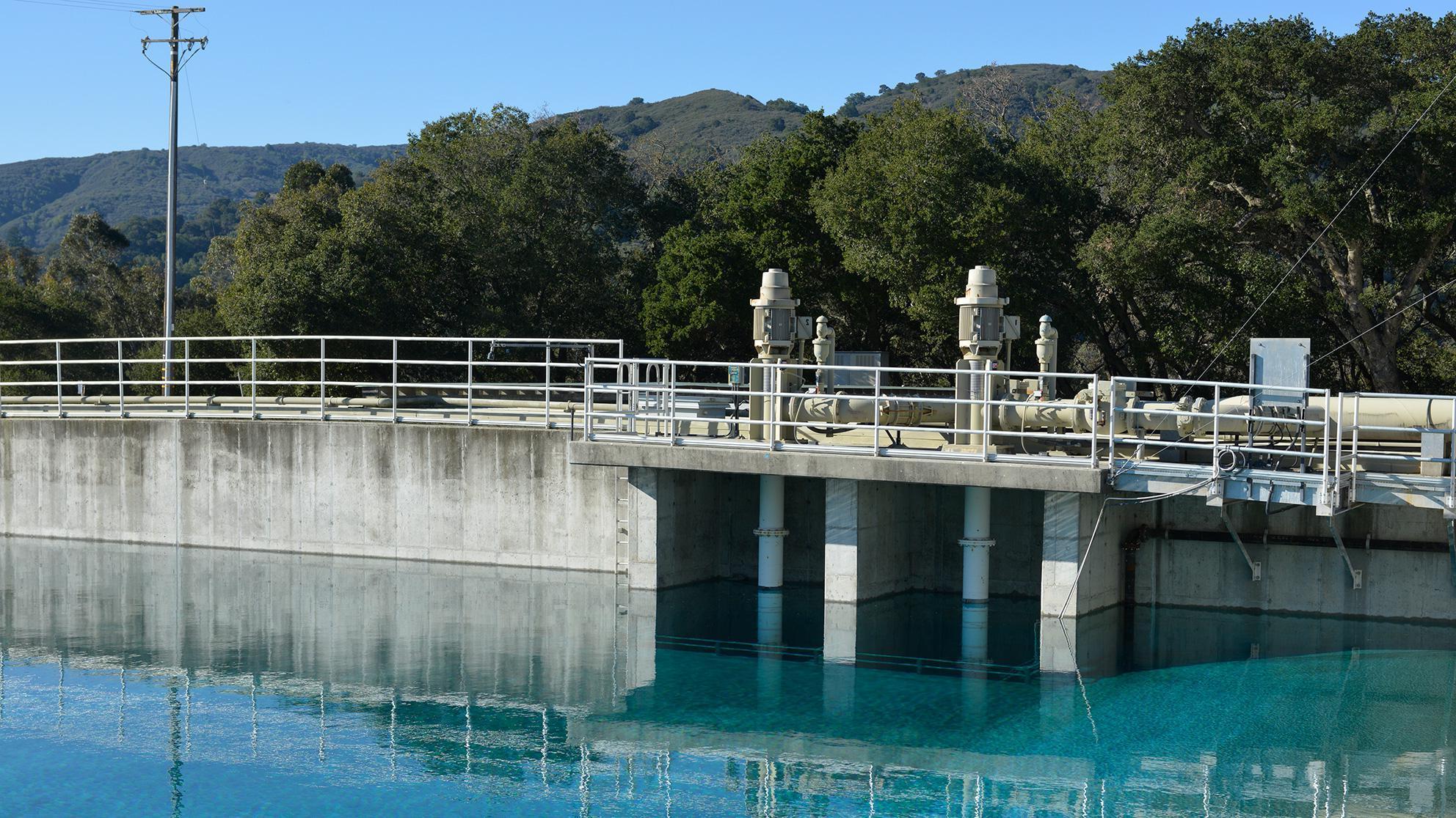 Water reservoir with green hills and blue sky in the background